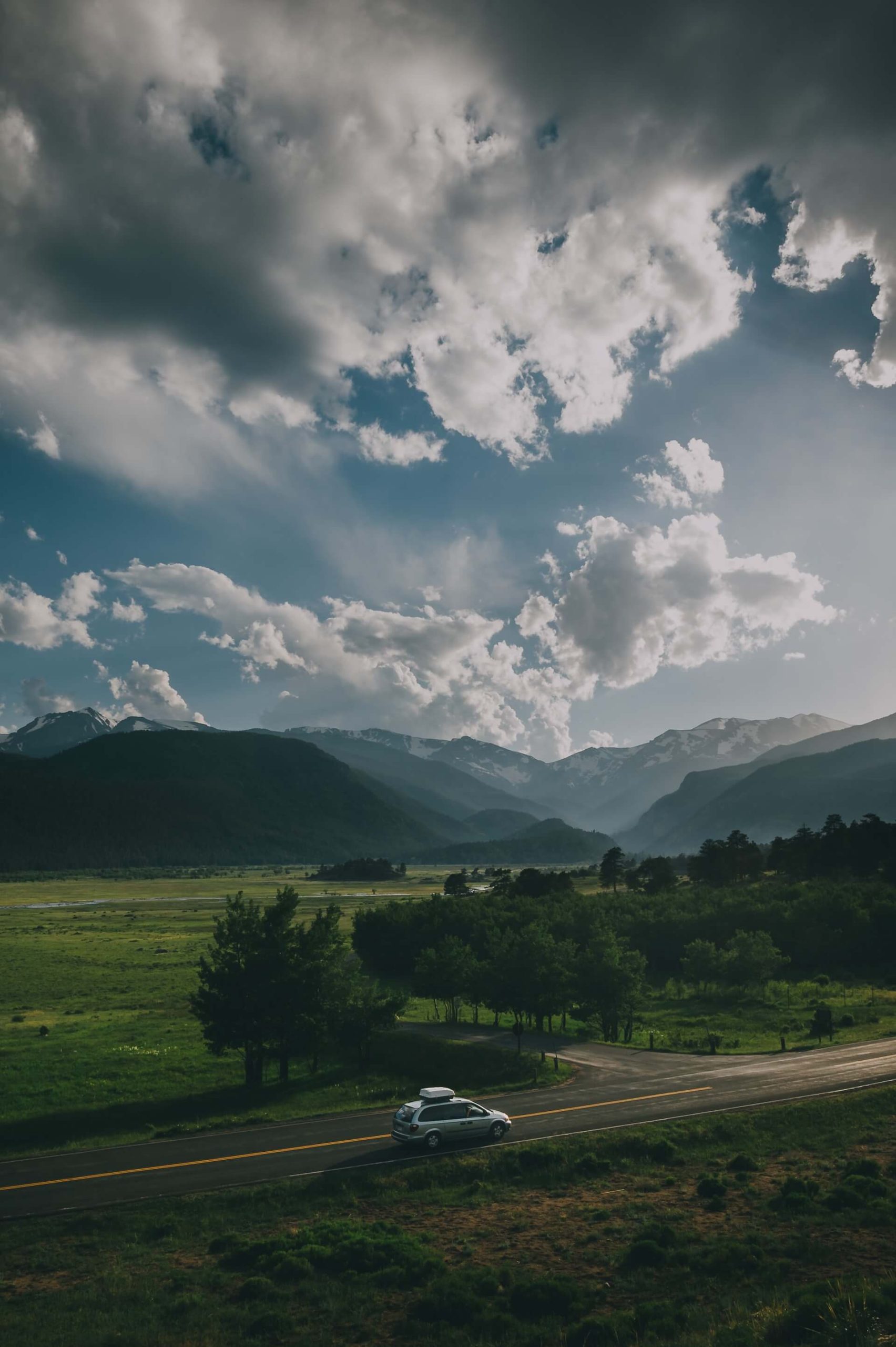 Fin bild på en bil som åker bland fina berg och natur.